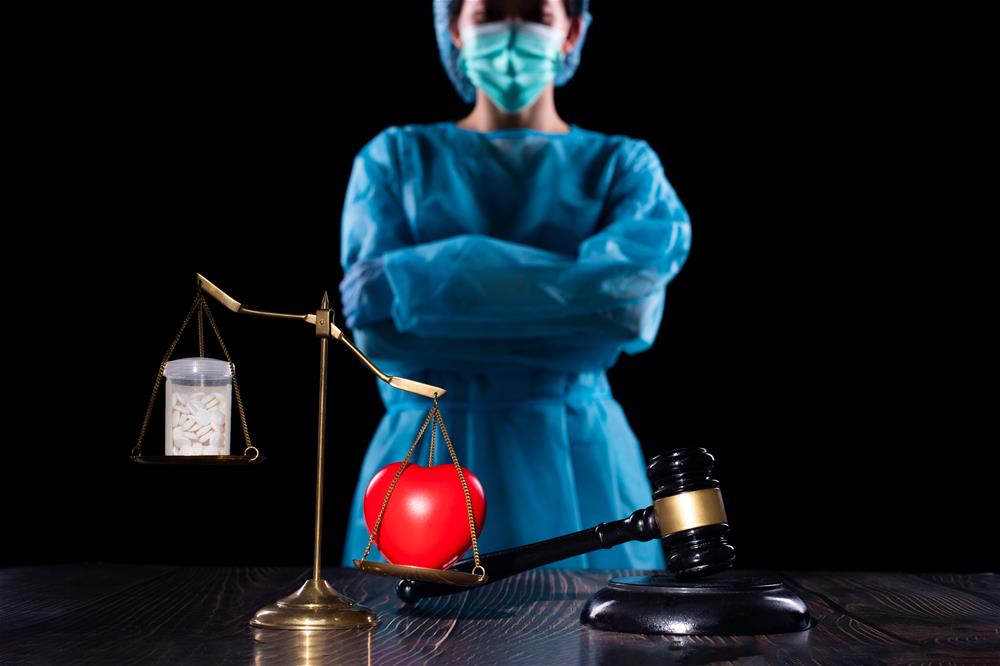 Picture of scales weighing drugs versus a heart in front of a healthcare professional in PPE