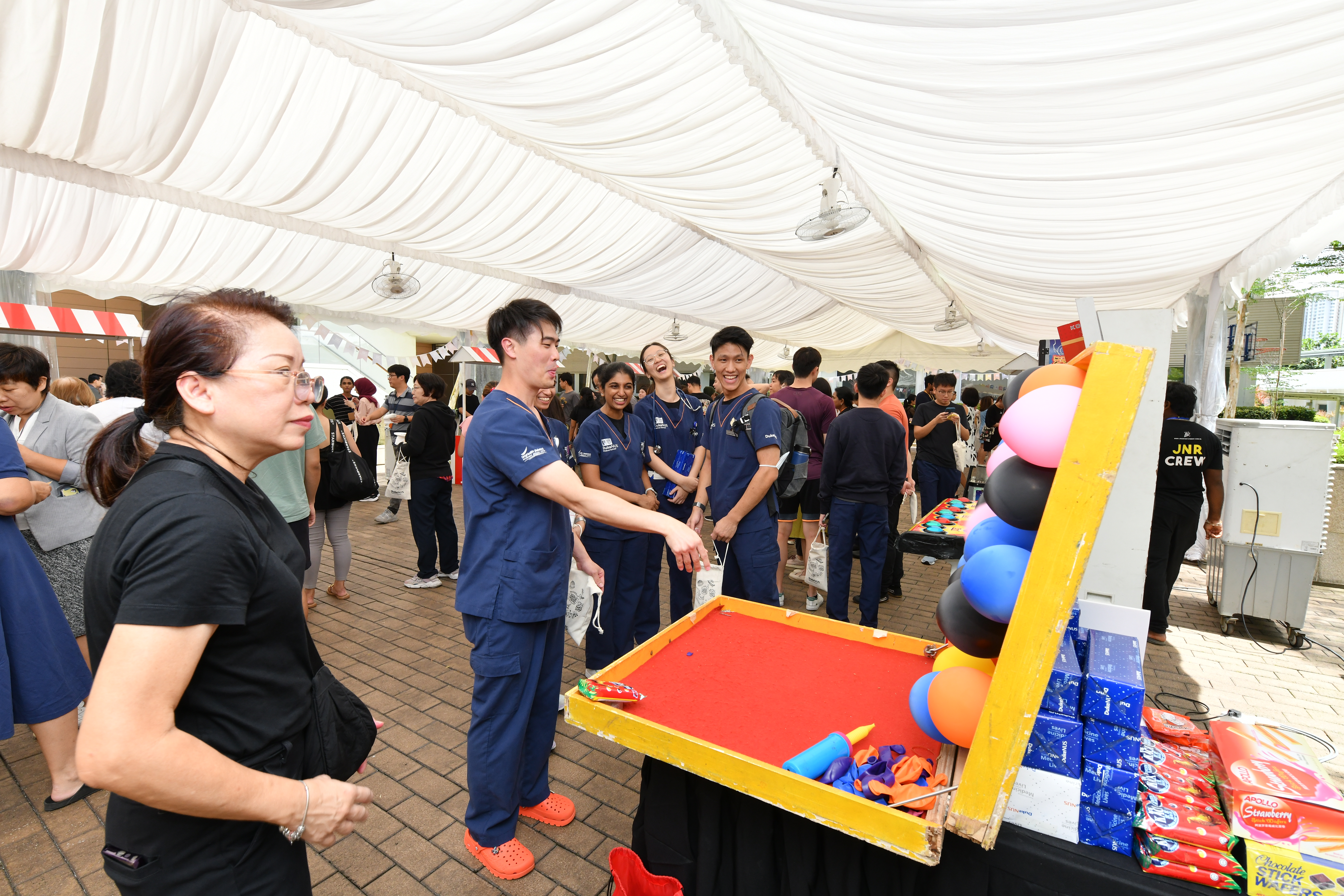 This picture shows Duke-NUS medical students enjoying traditional carnival games with a crowd in the background