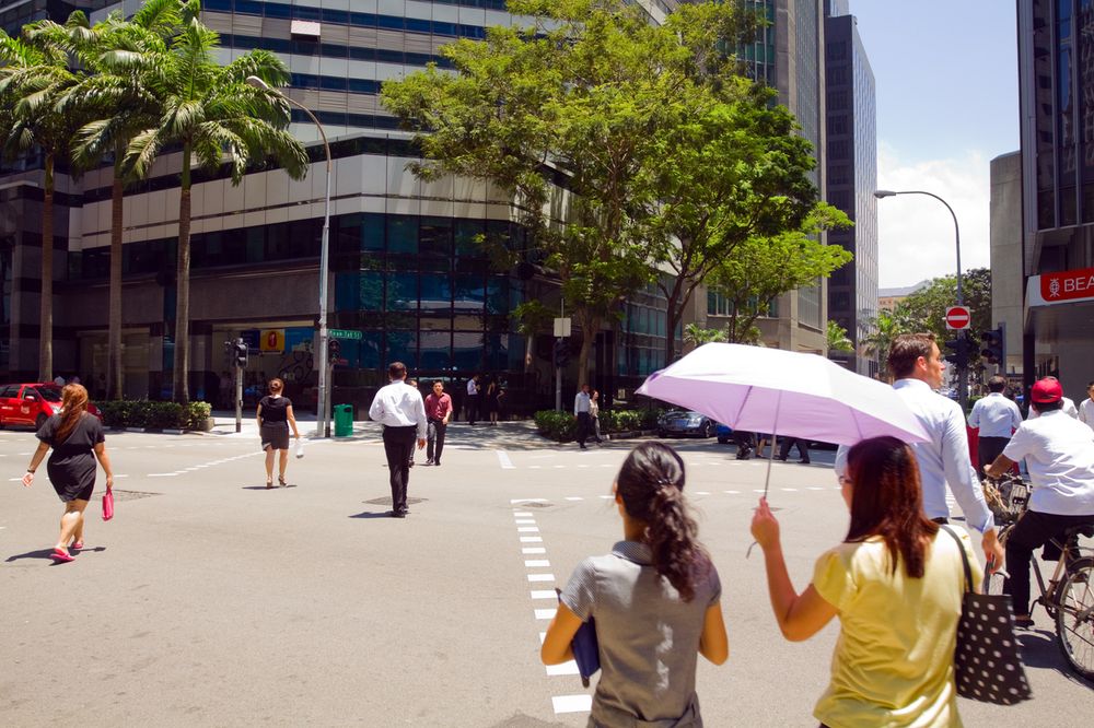 People in Singapore walking in the hot and humid weather with their umbrellas for shade