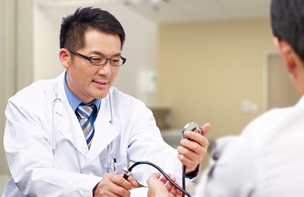 A general practitioner taking the blood pressure of a patient