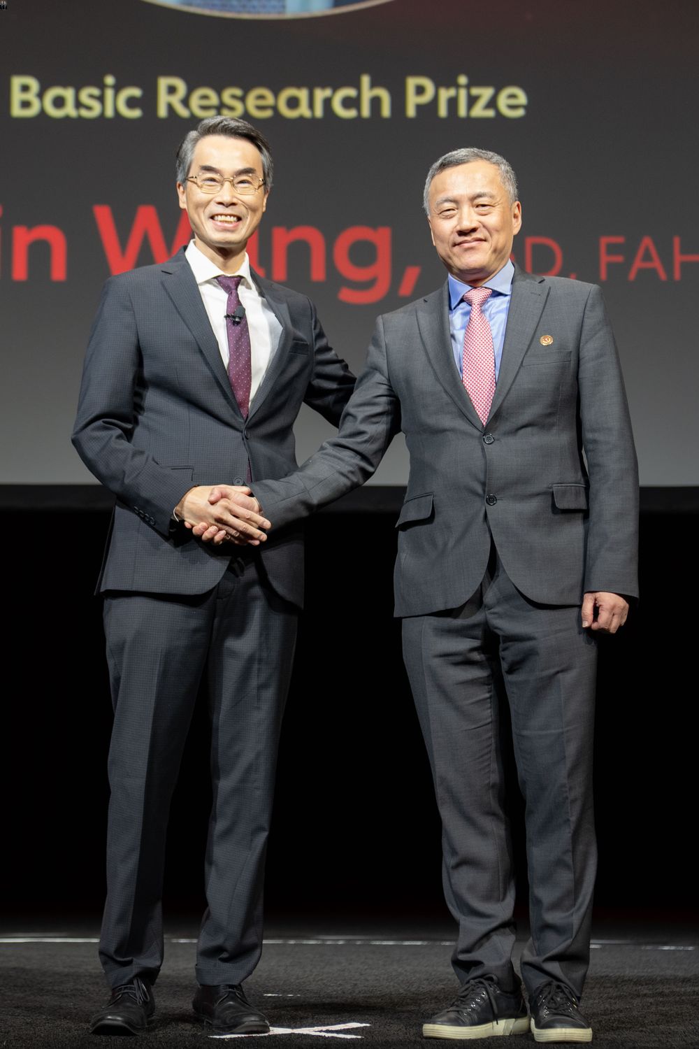 Wang Yibin, right, accepts the American Heart Association&#39;s Basic Research Prize 2023 on stage during the Association&#39;s annual conference