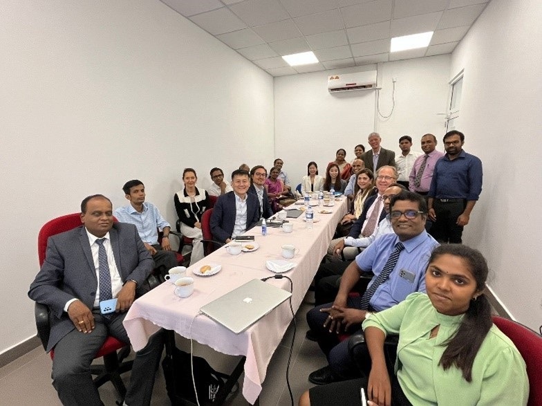 Jaffna working group meeting A group of people sitting around a long rectangular conference table with more people standing behind them