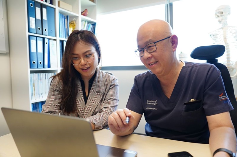 Duke-NUS MD programme alumnus Dr Marjorie Hoang and her mentor Prof Pierce Chow An Asian woman and man discuss information displayed on a computer