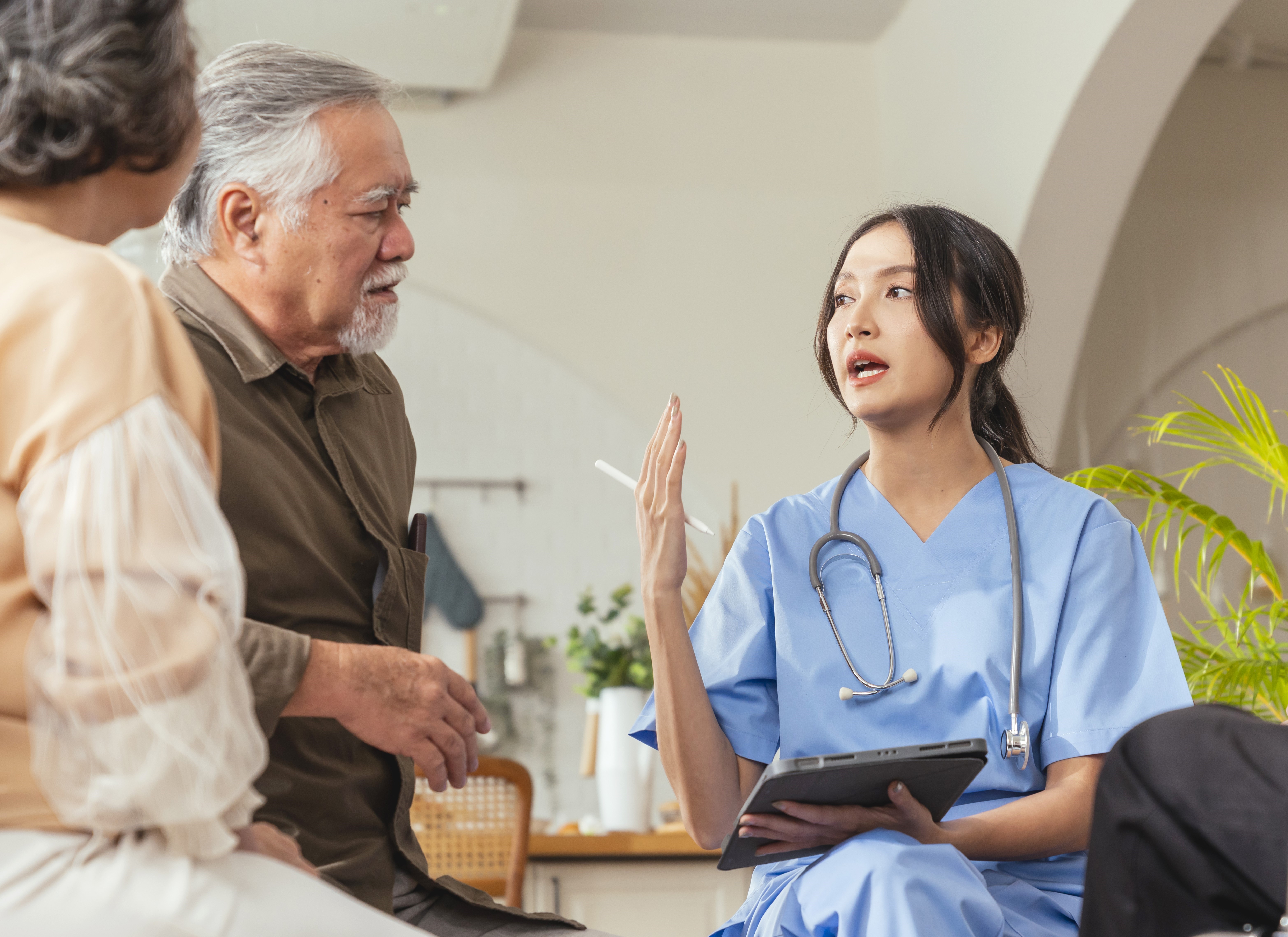happiness-cheerful-elderly-woman-men-talking-with-female-caregiver-nurse-doctor-having-health-checking-consult-living-areacaretakers-with-senior-couple-sitting-living-room-nursing-home