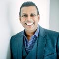 photo of ramesh raj kishore smiling in an emerald suit and a blue and white polka-dotted shirt