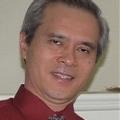 Souly Phanouvong smiling in a red shirt and grey tie